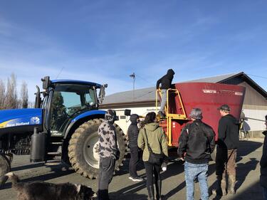 Highschool Students standing and looking at blue tractor