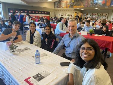4 students and City of Abbotsford Mayor sitting at a table