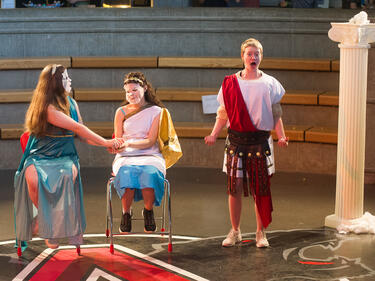 Three students dressed in costume performing