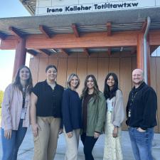 Six smiling teacher candidates standing in front of school