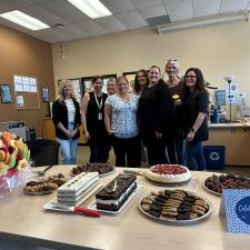 Group of staff smiling in front of table of treats